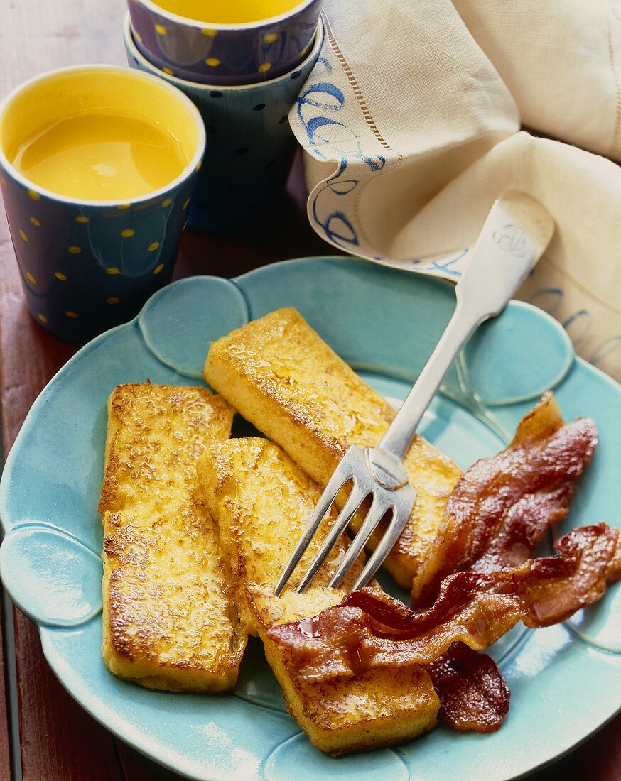 Drei Stücke French Toast mit gebratenem Speck und Orangensaft