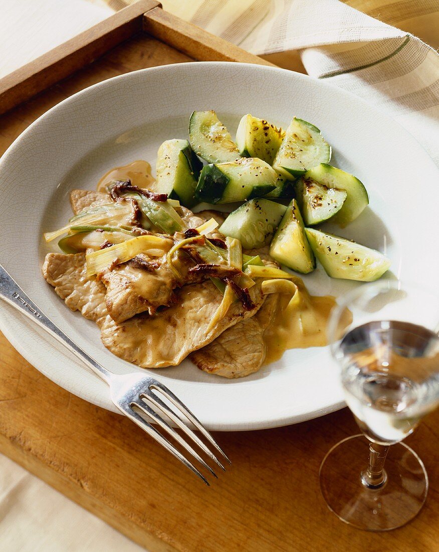 Turkey Cutlets Topped with Sun Dried Tomatoes and Leeks Served with Grilled Cucumbers on a Plate; Fork
