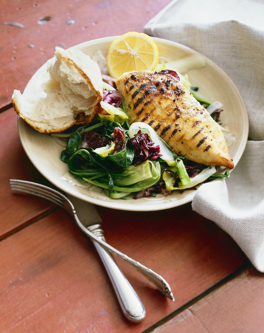 gegrillte Hühnerbrust mit Salat und einem Stück Brot