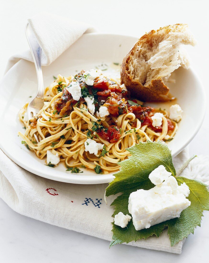 Plate of Pasta with Tomatoes and Goat Cheese; Piece of Crusty Bread
