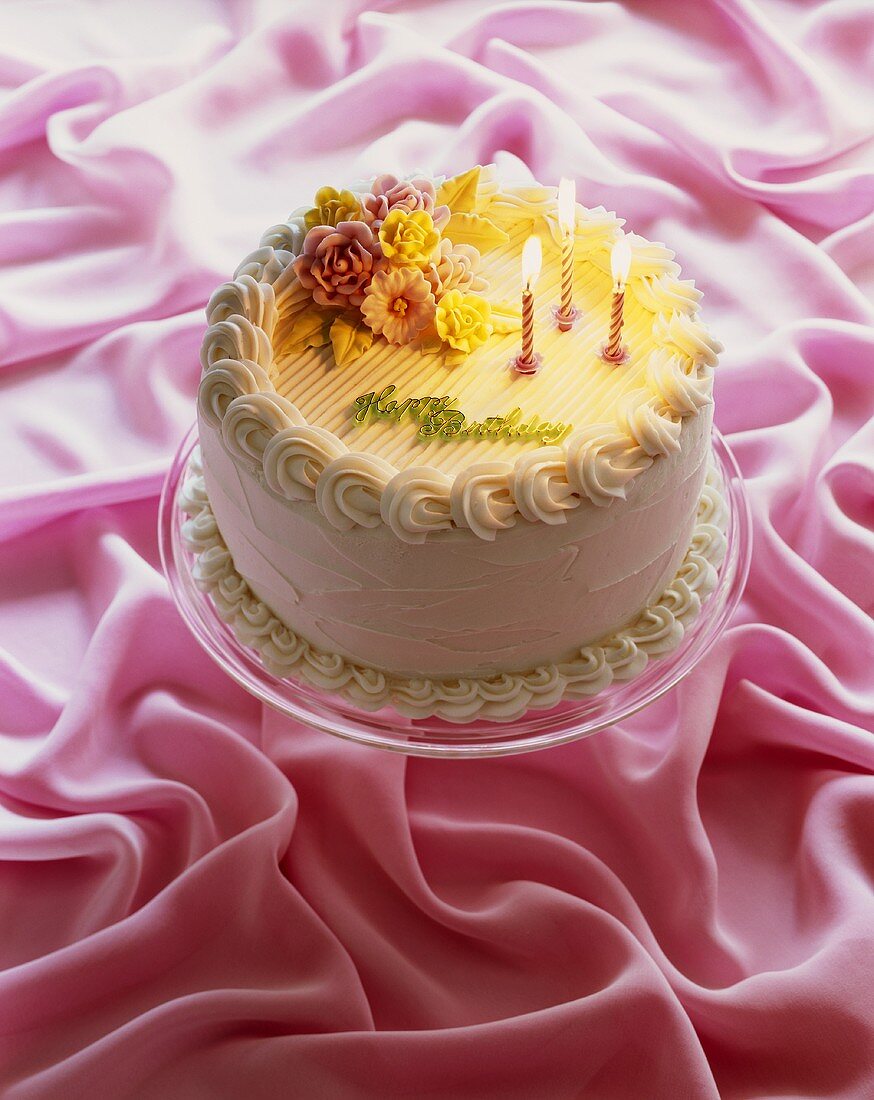 Happy Birthday Cake with Three Pink Lit Candles; On Pink Cloth