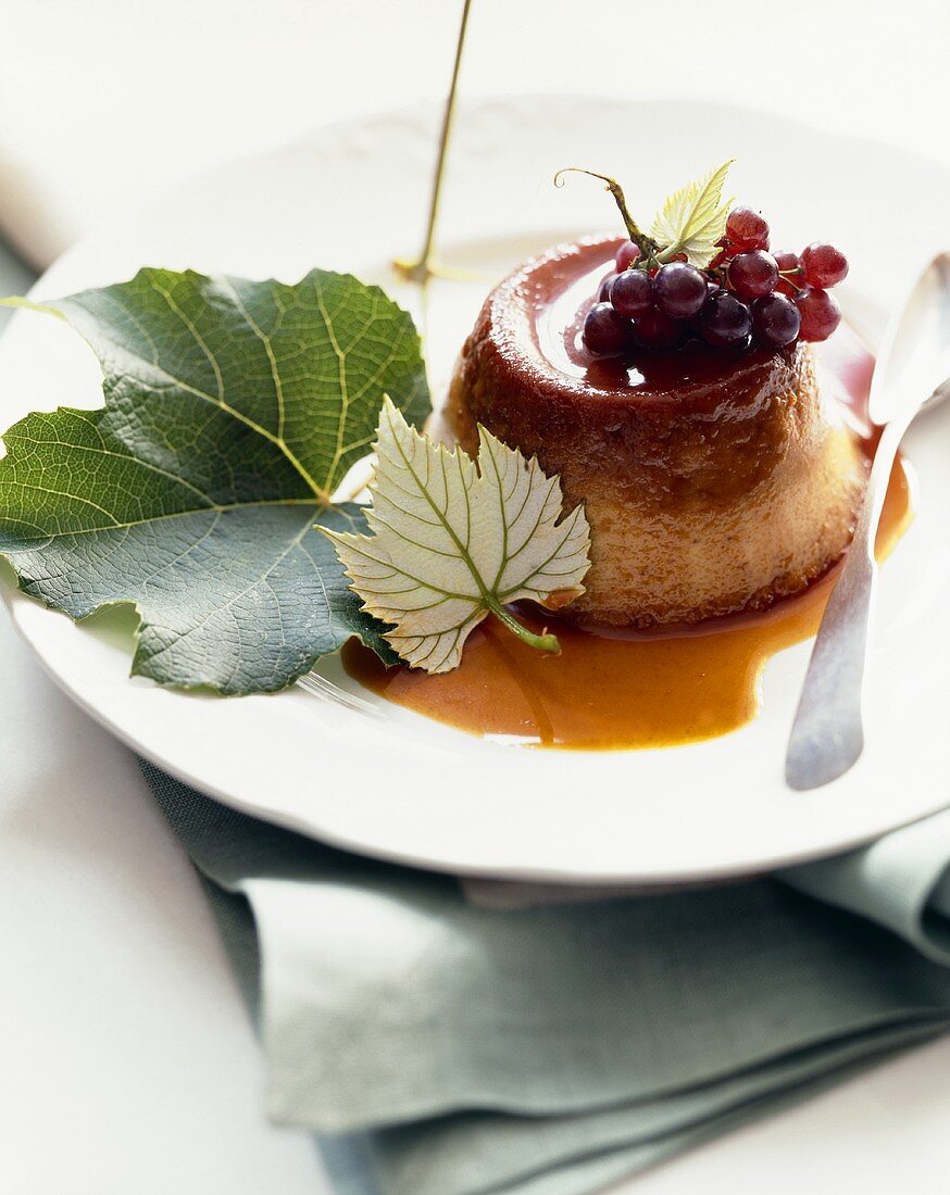 Cr?me Caramel with Currant Topping on a Plate with Spoon and Leaves