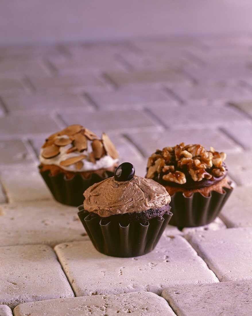 Drei Cupcakes (Schokolade-Mokka, Schokolade-Walnuss, Vanille-Mandel)