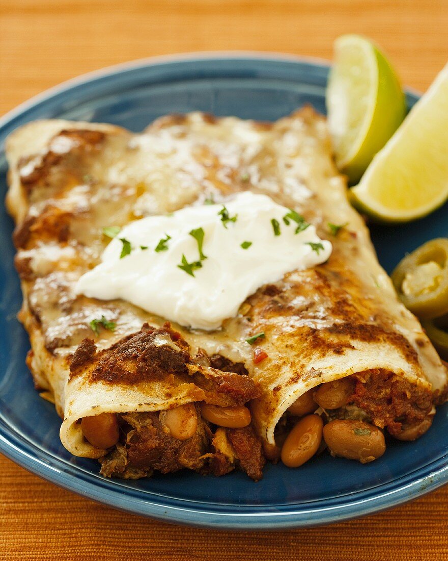 Two Beef and Bean Enchiladas on a Plate with Sour Cream