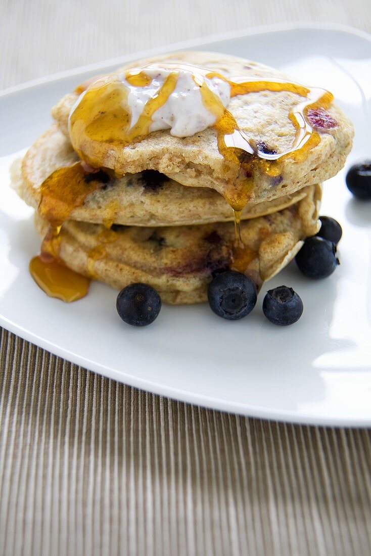 Wholemeal Blueberry Pancakes with Butter and Maple Syrup; On White Plate