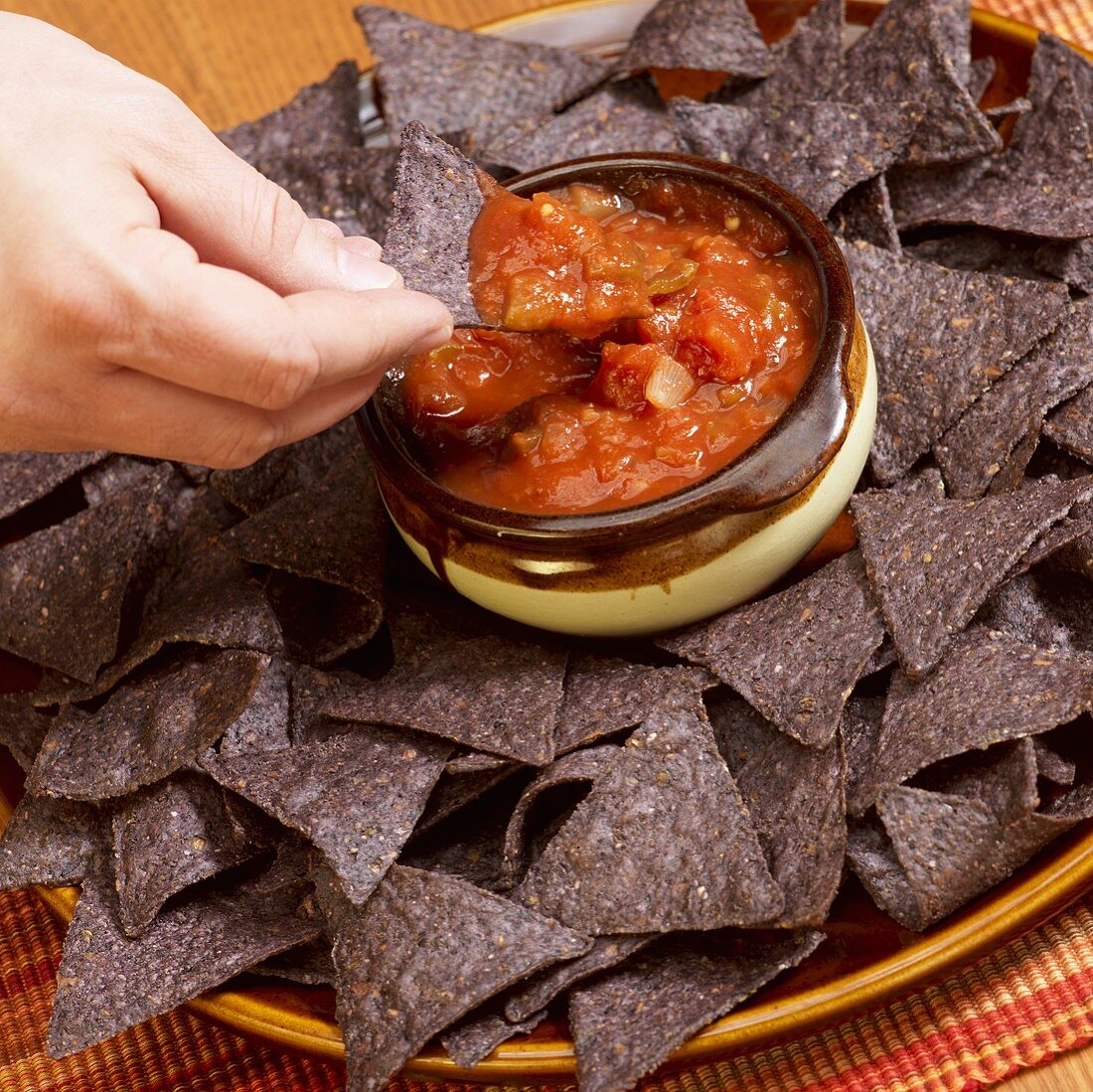 Hand Dipping Blue Corn Chip into Salsa