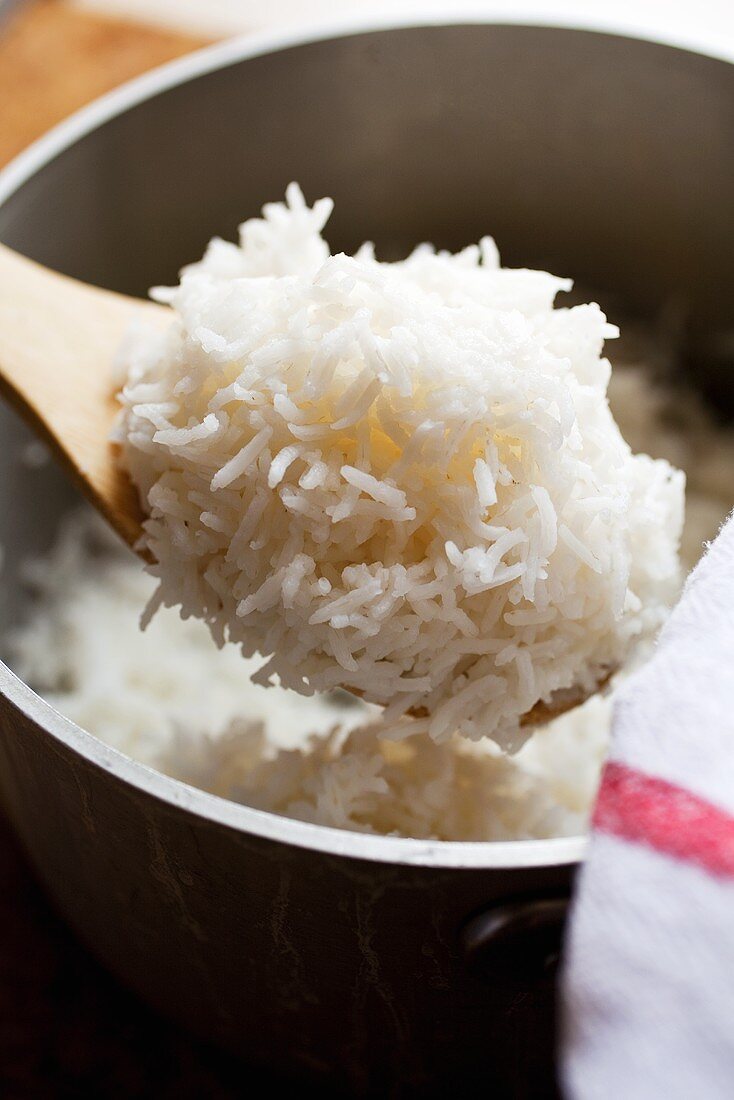 Gekochter Reis auf Kochlöffel über Topf
