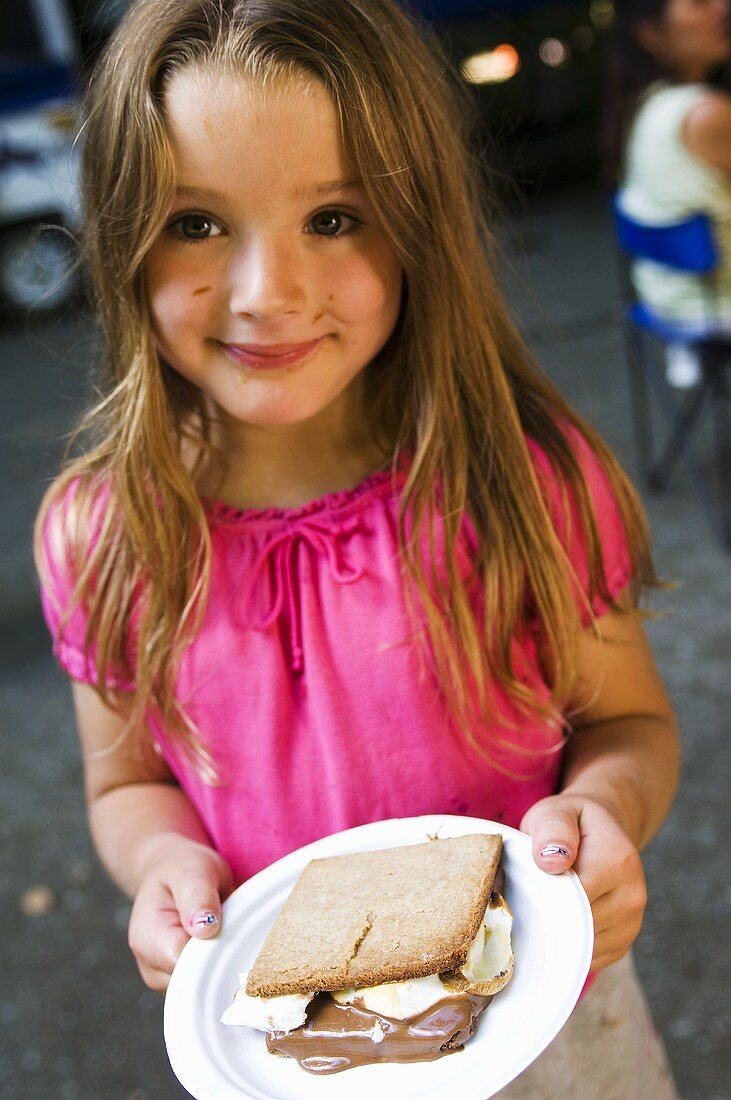 Young Girl Holding a Plate with a S'more; Chocolate on Her Face