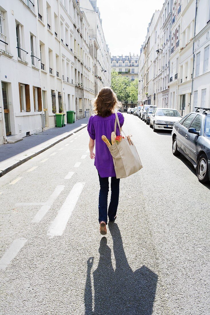 Woman Walking down the Street in Paris France with a Cloth Bag; Baguette and Flowers