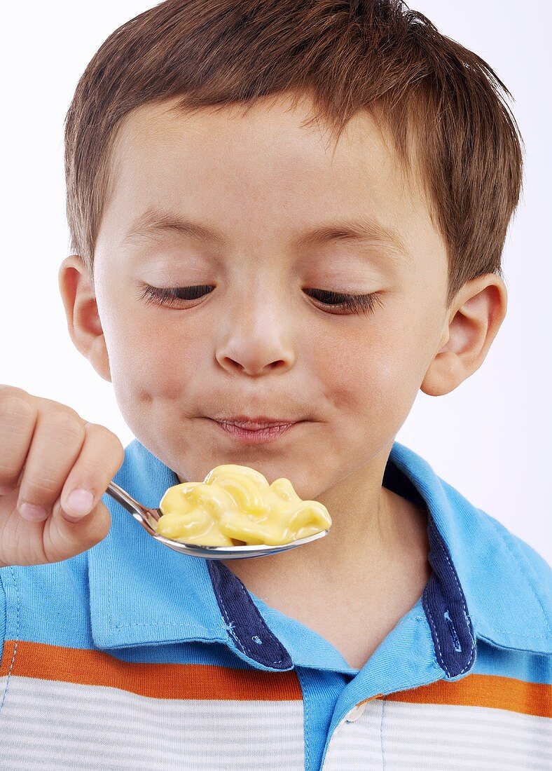 Kleiner Junge hält Löffel mit Macaroni and Cheese