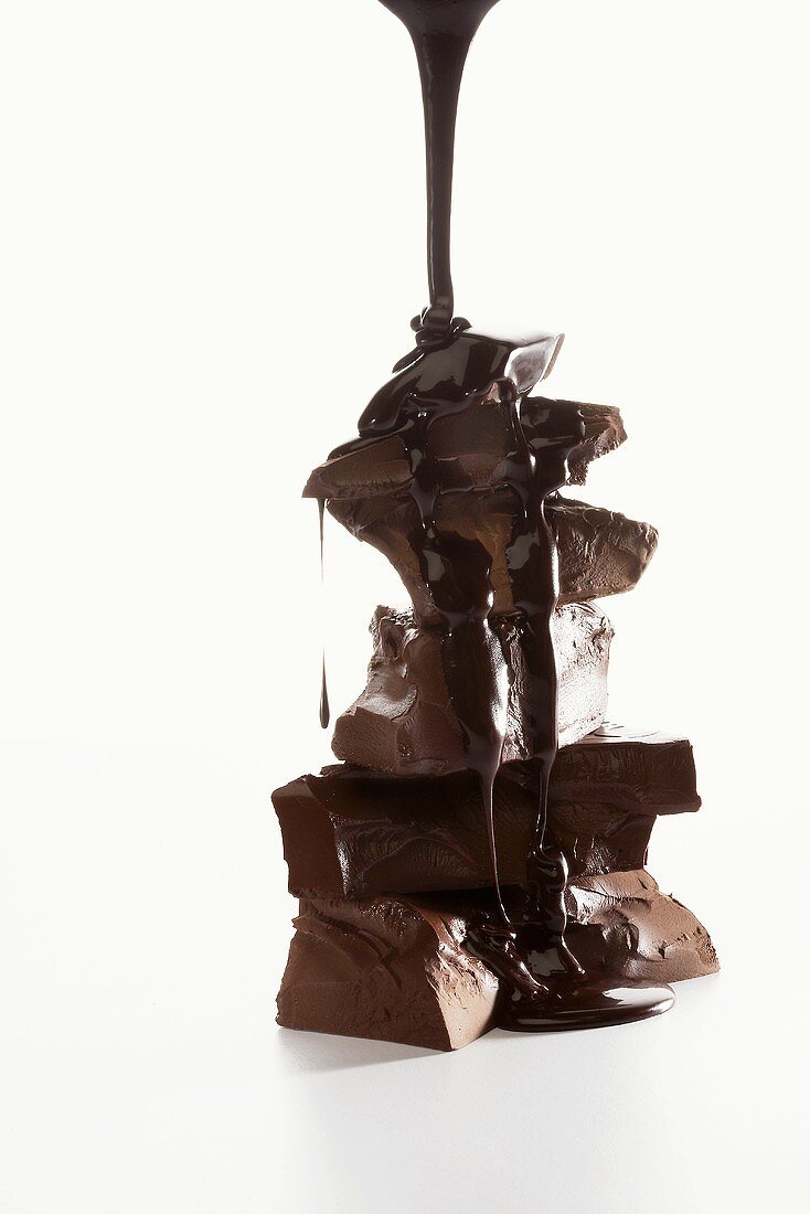 Schokoladensauce fliesst über gestapelte Schokoladenstücke