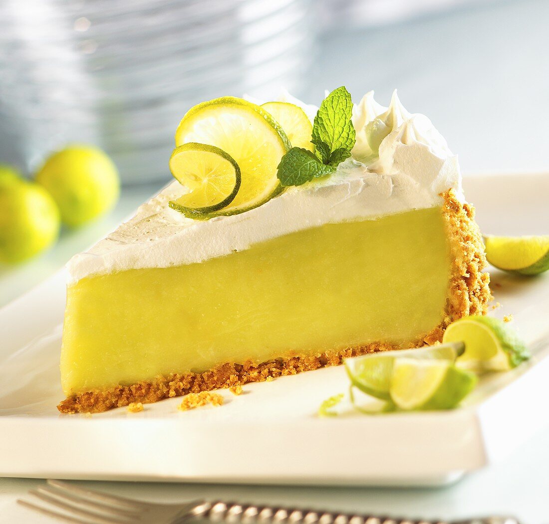 Slice of Key Lime Pie on a White Plate; Lime Wedges