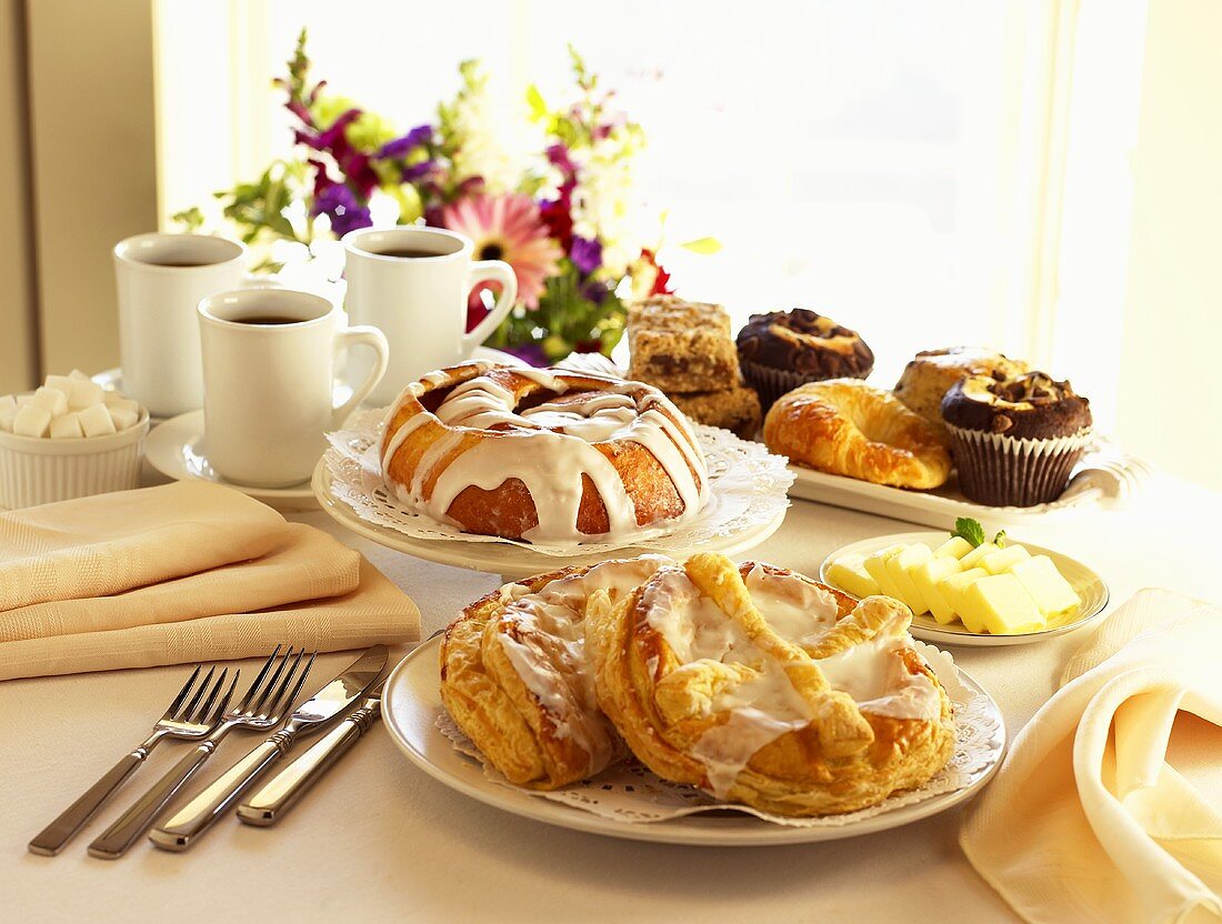 Frühststückstisch mit süssem Gebäck, Butter und Kaffee