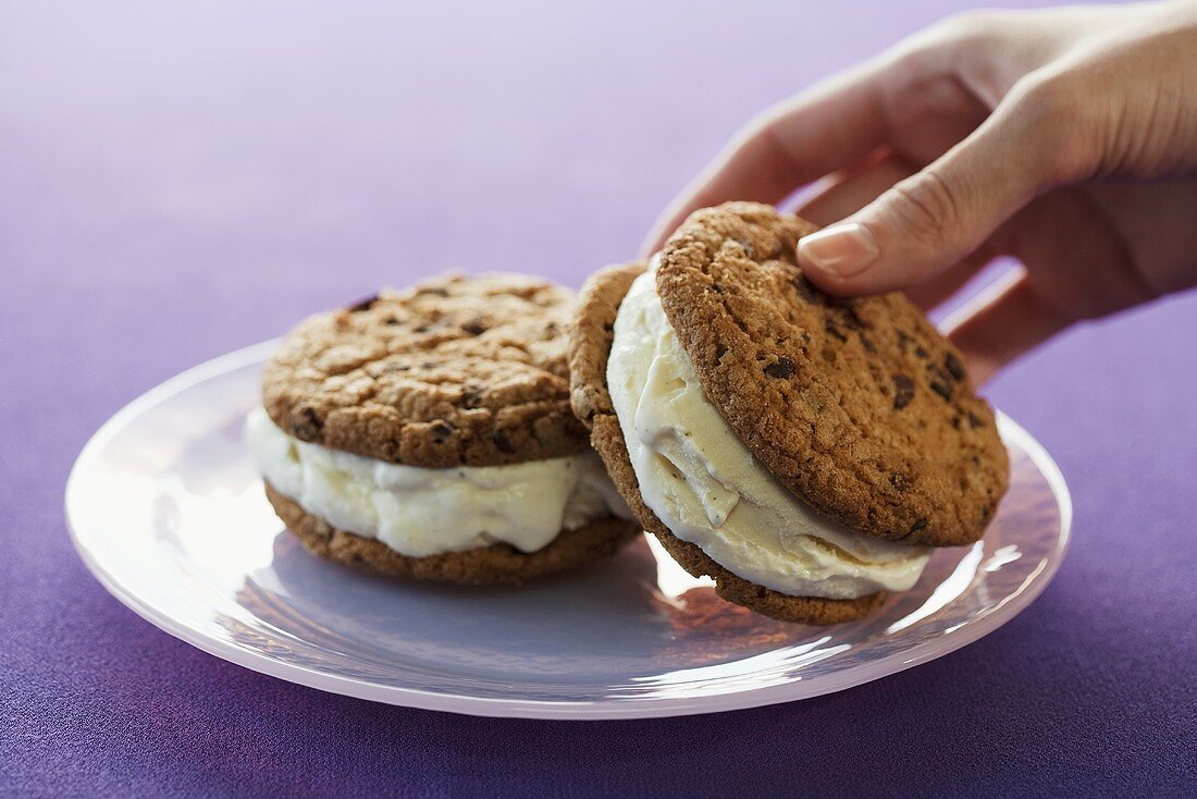 Hand Picking Up Cookie Ice Cream Sandwich from Plate