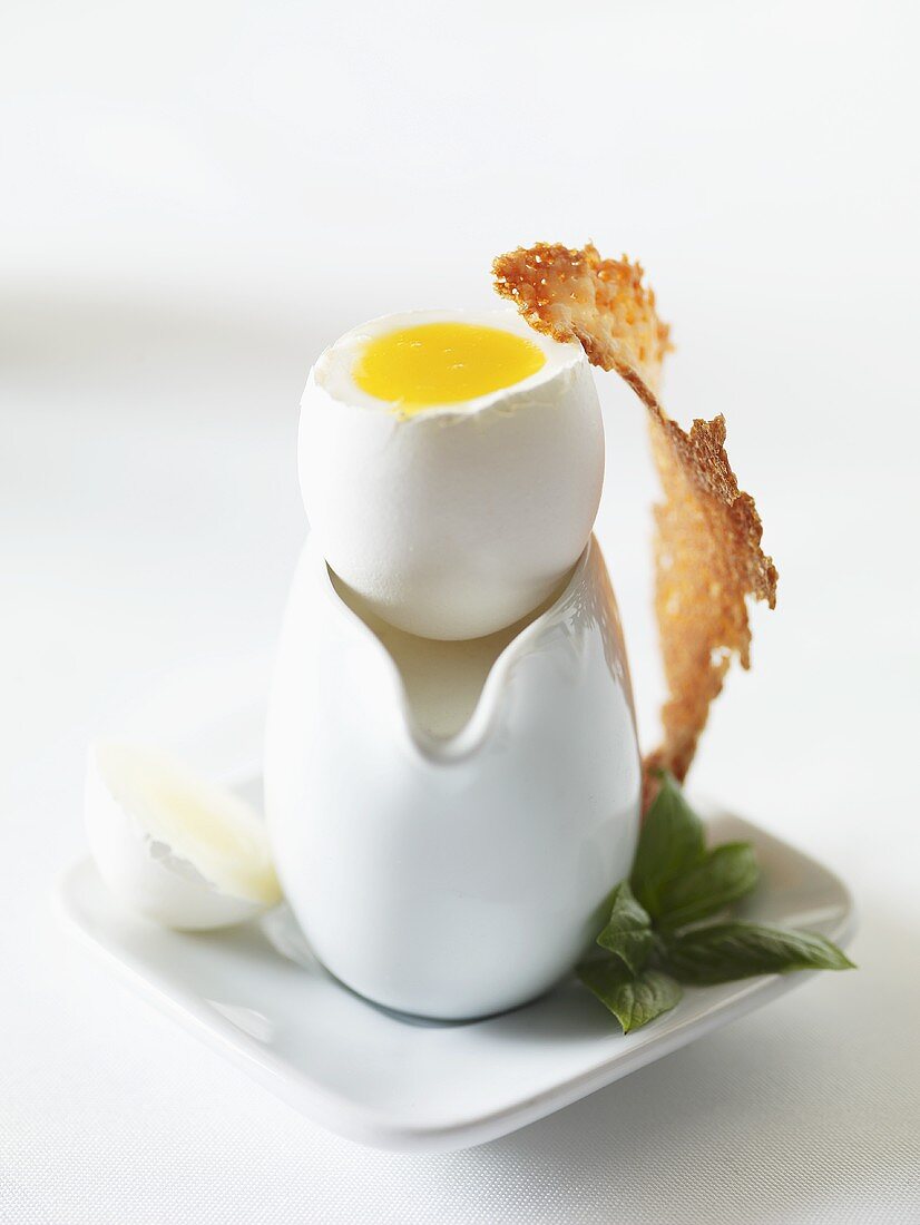 Weichgekochtes Ei mit Käsecracker und Basilikum