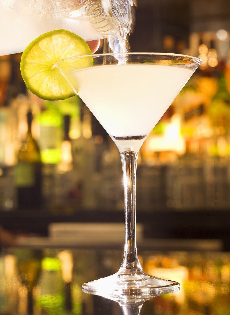 Pouring a Lemon Drop Martini into a Glass from Pitcher; On Bar