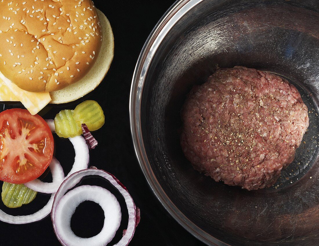 Raw Hamburger Patty in a Bowl; Toppings and Bun