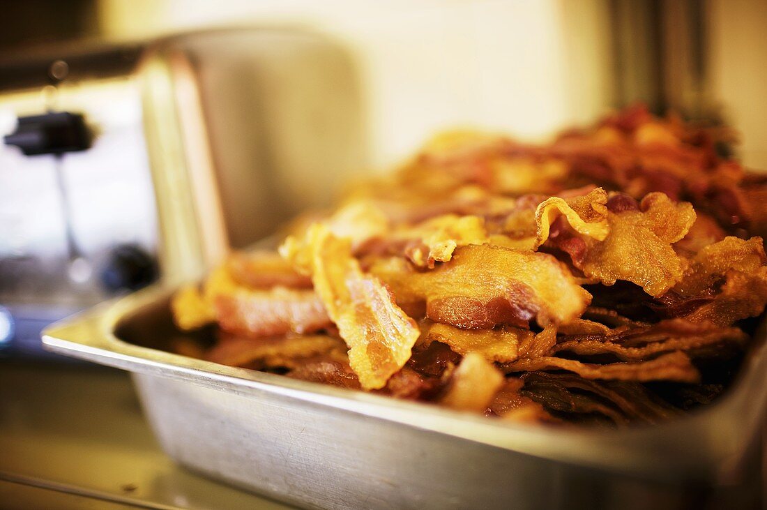 Viele knusprige Baconscheiben auf Tablett in Restaurantküche