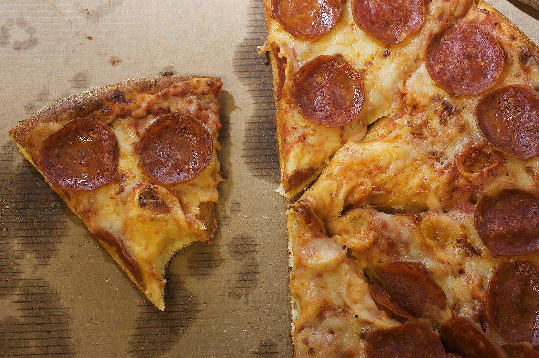 Pizza mit Peperoniwurst, ein Stück angebissen