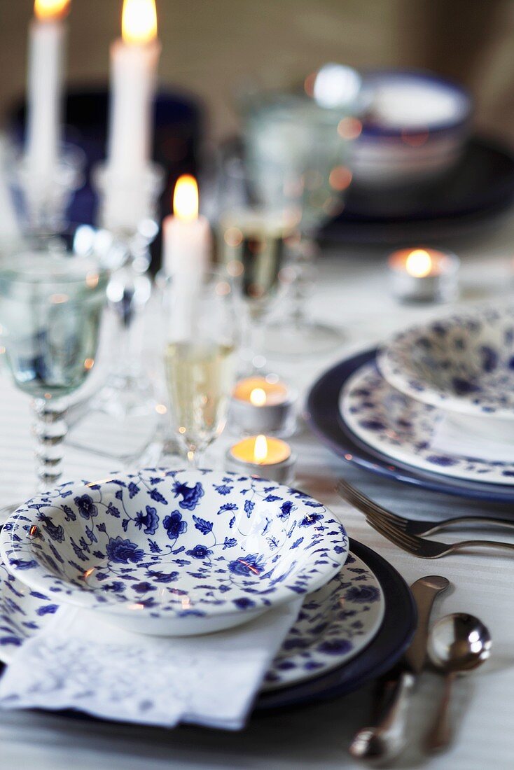 Geschirr mit Blumenmuster, Kerzen und Weingläser auf Tisch