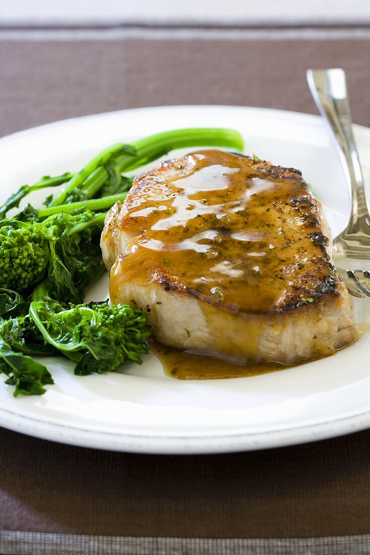 Pork Chop with Sauce and Broccolini on a White Plate