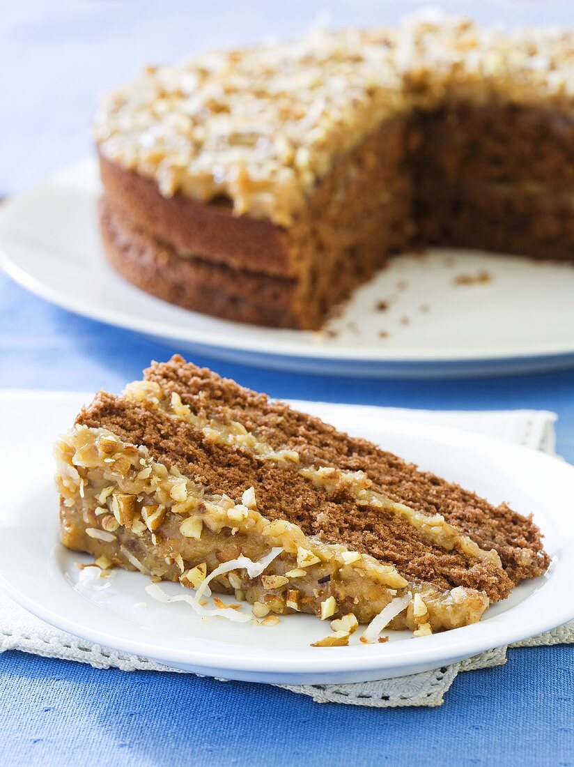 Slice of German Chocolate Cake on a White Plate; Whole Cake