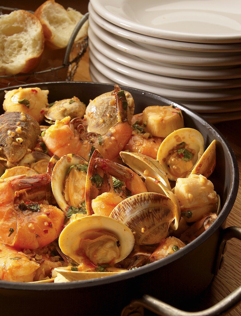 Seafood Stew in a Large Pot; Stack of Bowls; Bread