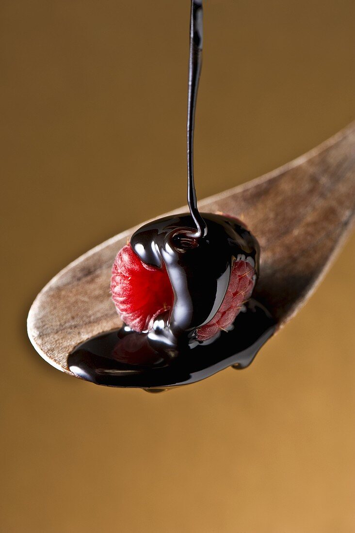 Raspberry on a Wooden Spoon with Dark Chocolate Pouring Over It