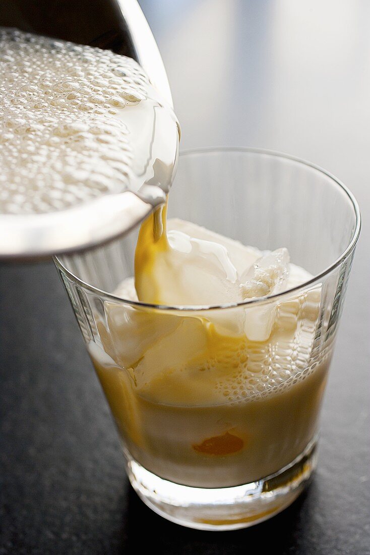 Pouring Milk Punch into a Glass with Ice