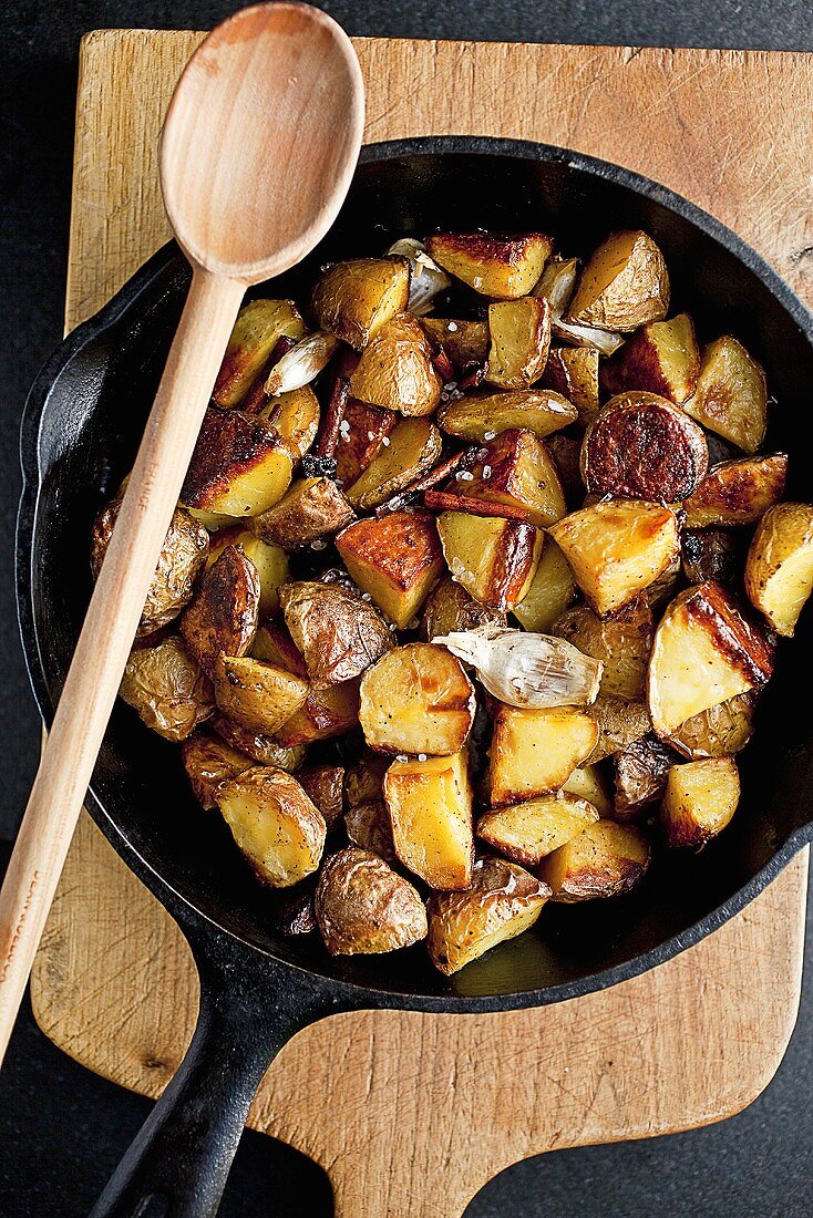 Cinnamon Roasted Potatoes in a Cast Iron Skillet; With Wooden Spoon; From Above