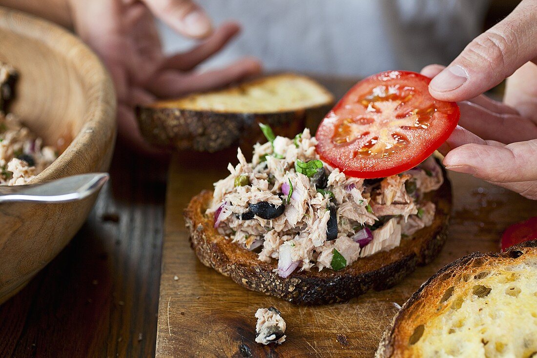 Thunfisch-Sandwich mit Tomate belegen