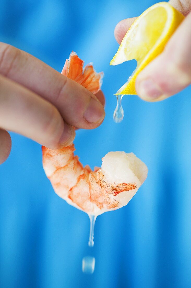 Hand Squeezing Lemon Onto a Shrimp