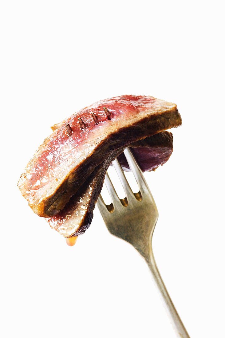 Two Slices of Rare Steak Pierced on a Fork