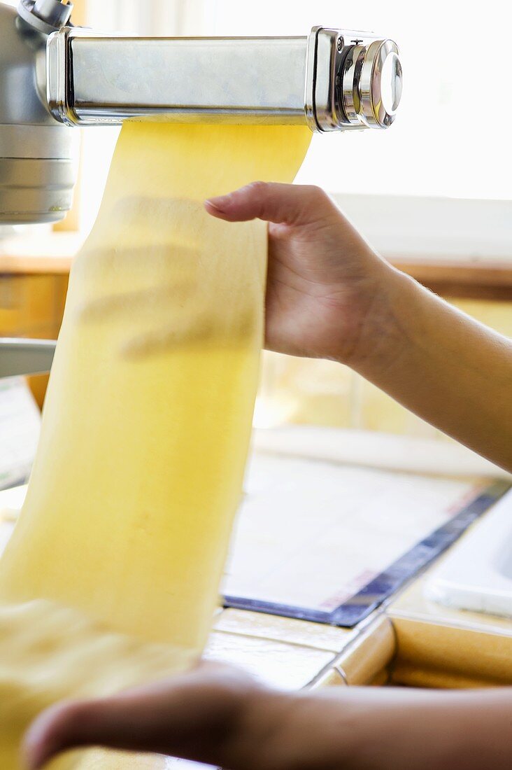 Person Supporting Fresh Pasta Coming Out of Machine