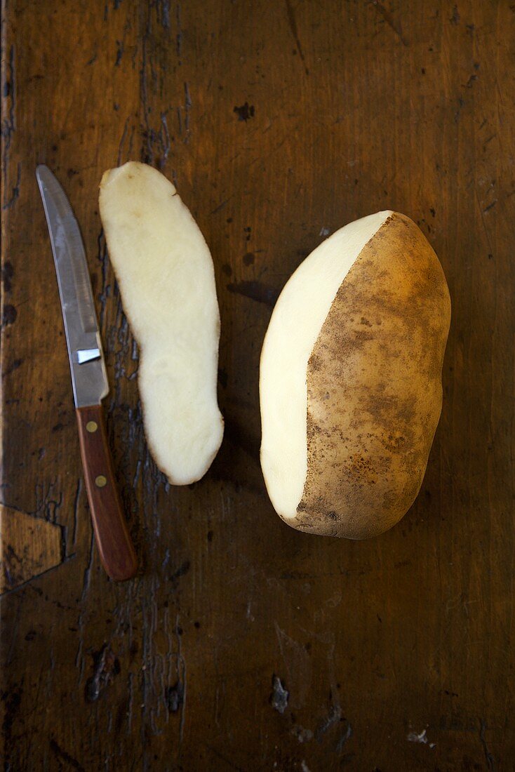 Idaho Kartoffel, teilweise geschält, daneben Messer