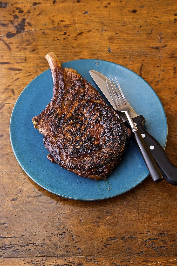 Grilled Steak on a Blue Plate; Knife and Fork