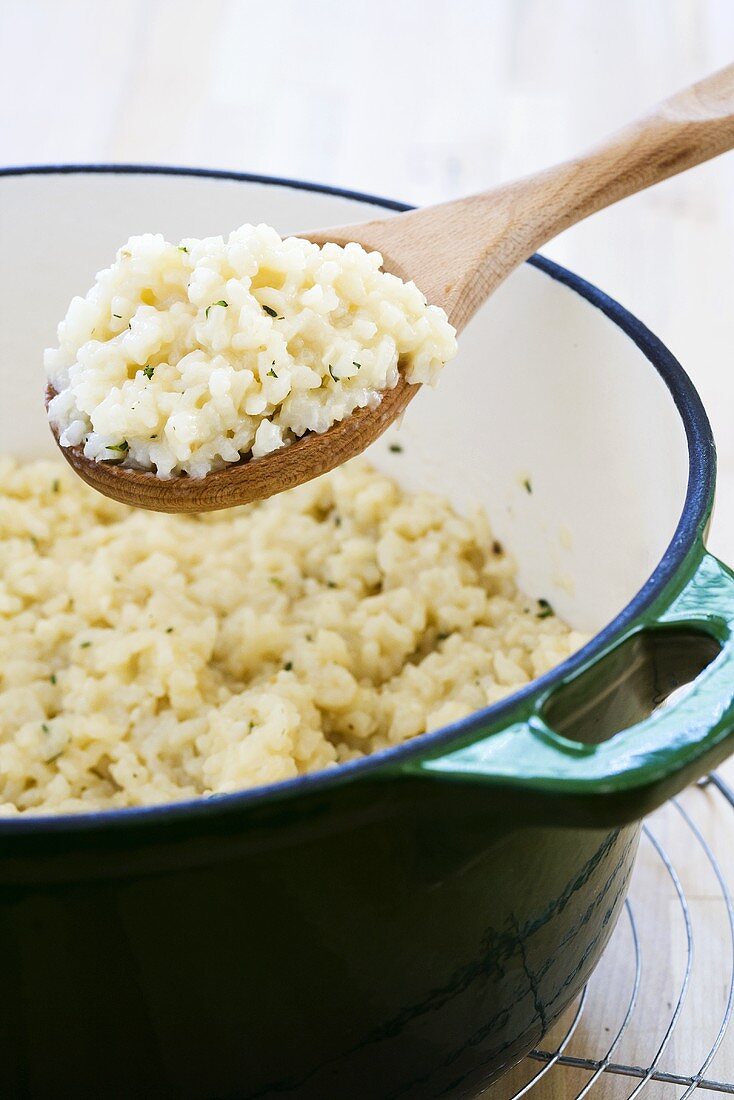 Risotto auf Kochlöffel über Kochtopf