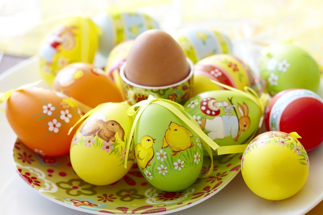 Ostereier aus Kunststoff und ein gekochtes Ei im Eierbecher