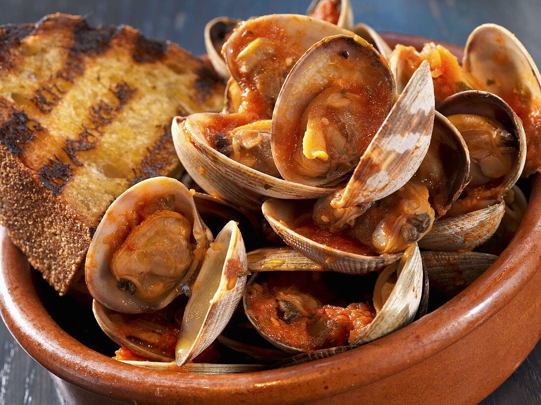 Bowl of Clams in a Tomato Sauce with a Slice of Grilled Bread