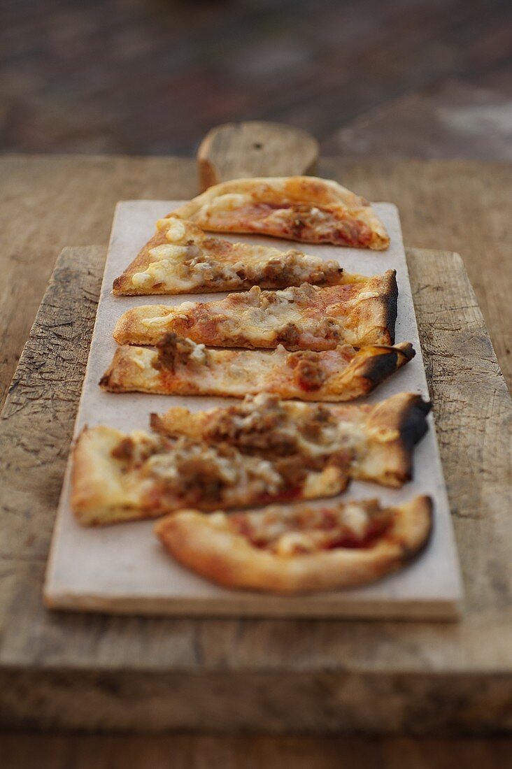 Holzofenpizza mit Wurst, in Stücke geschnitten