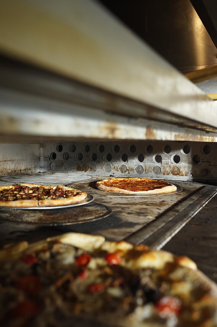 Two Assorted Pizzas Baking in a Pizza Oven