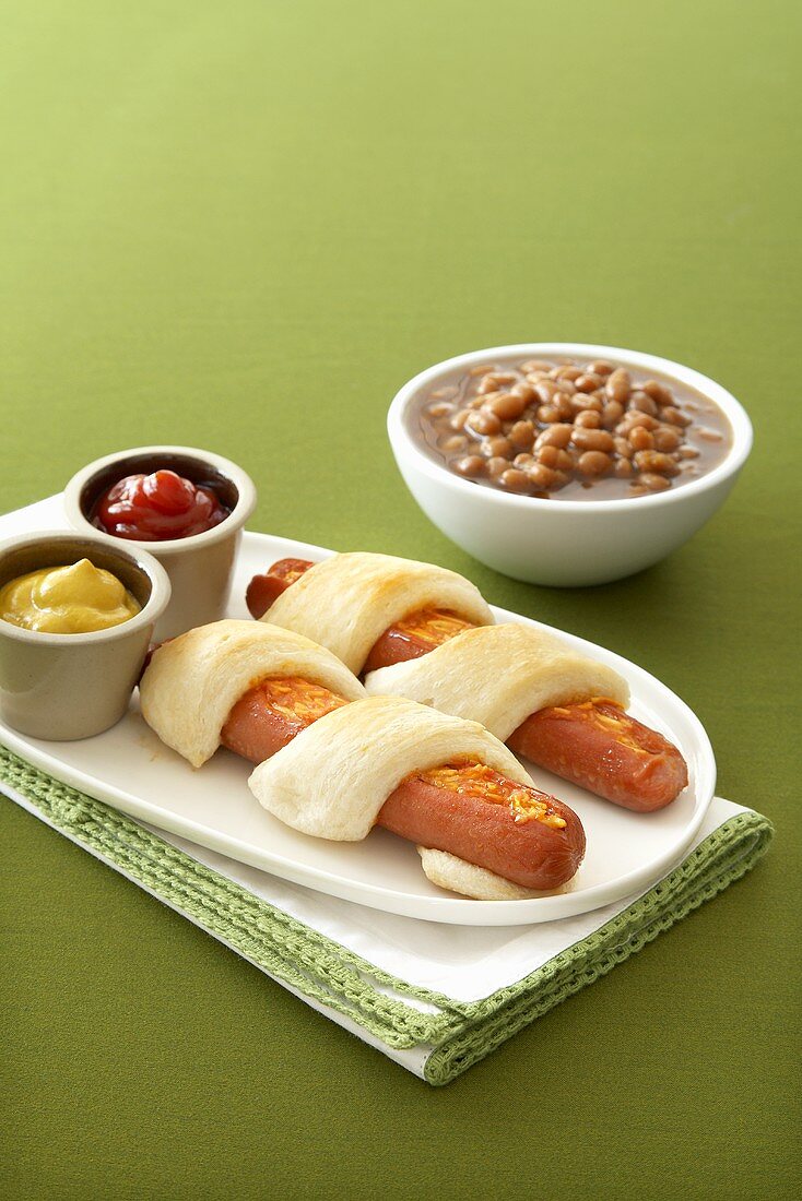 Stuffed Hot Dogs Wrapped and Baked in Pastry; Baked Beans; Ketchup and Mustard