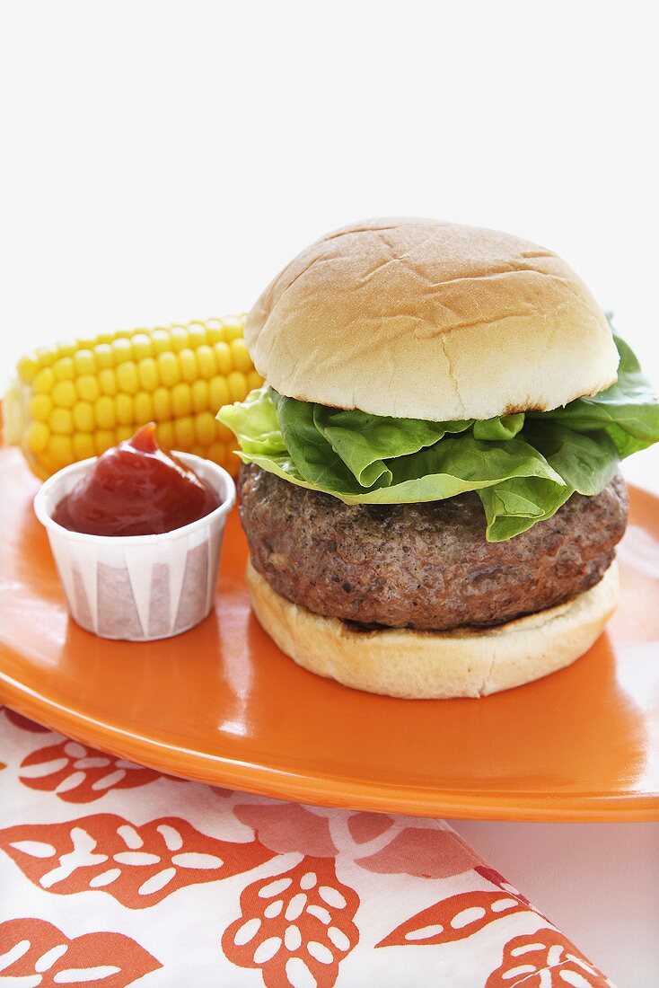 Stuffed Hamburger with Lettuce; Ketchup and Corn on the Cob