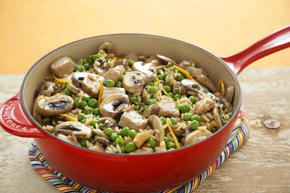 Pork and Rice Casserole with Peas and Mushrooms in a Red Pan