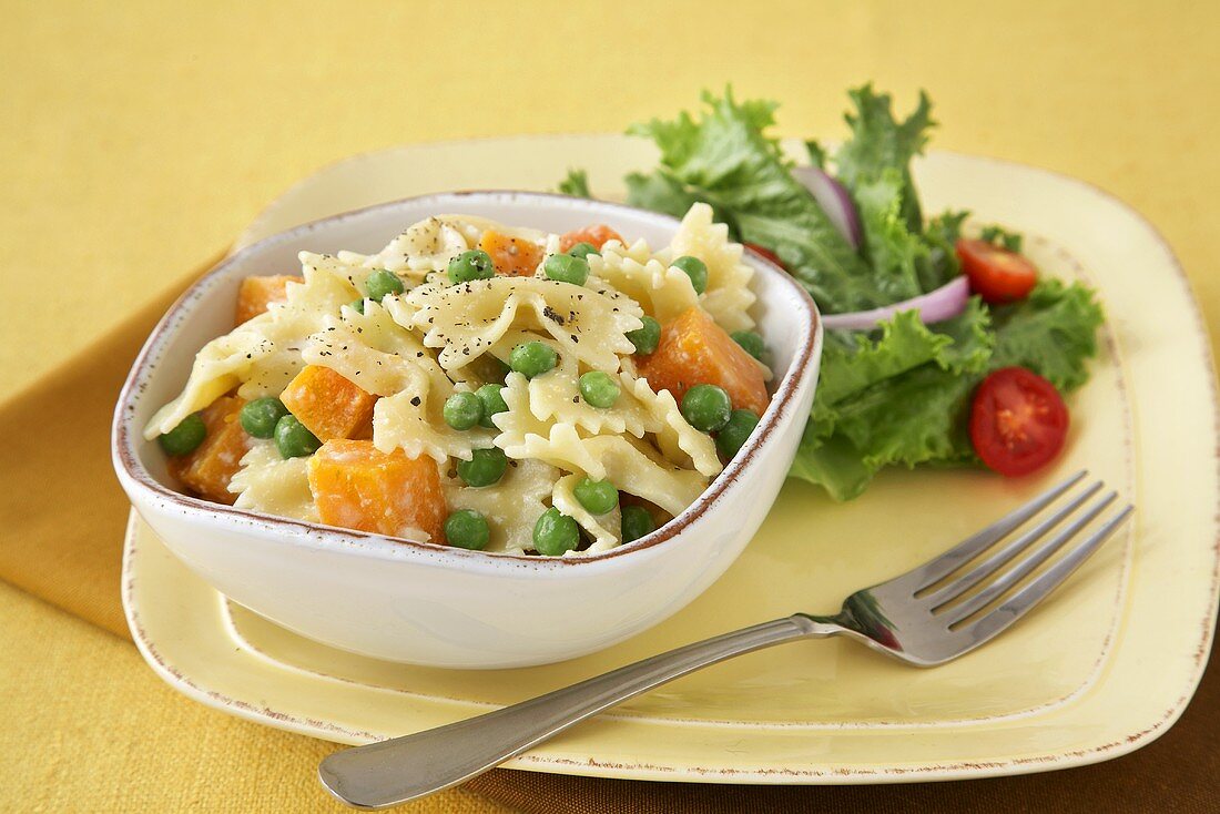 Farfalle Pasta with Peas and Squash in a Bowl; Fork; Side Salad