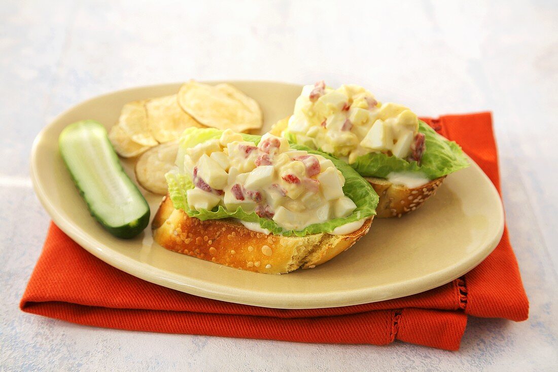 Opened Faced Egg Salad Sandwich with Pickle and Chips on a Plate