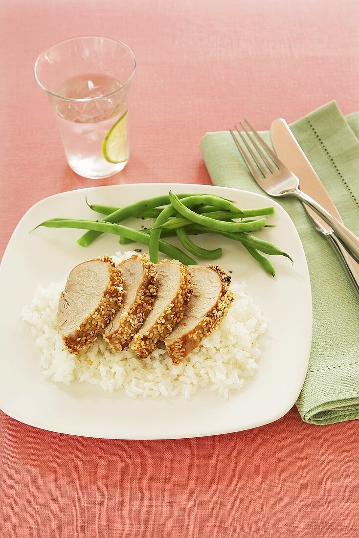Sliced Pork Tenderloin Over White Rice with Green Beans; Glass of Water with Lime