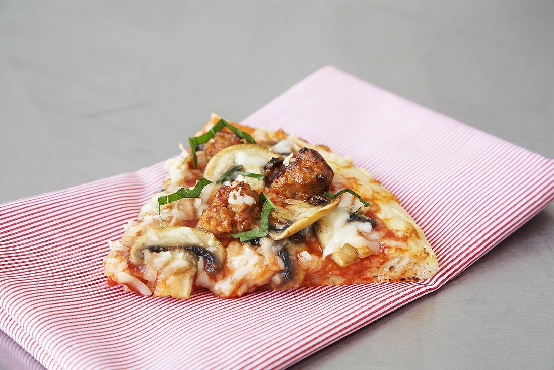 Slice of Sausage and Mushroom Pizza on a Striped Napkin