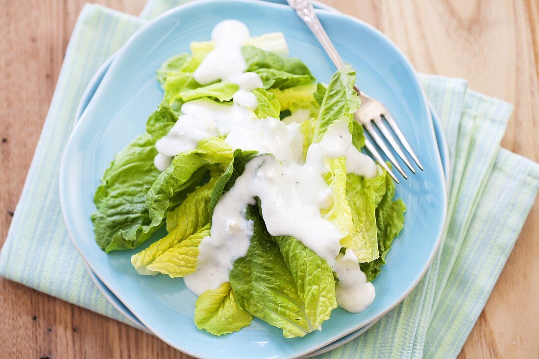 Romaine Lettuce with Creamy Dressing on a Blue Plate; From Above