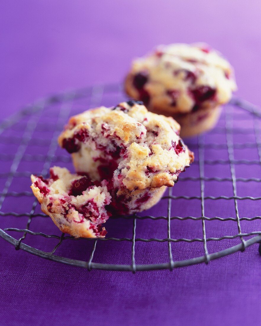 Two cranberry muffins on a wire rack